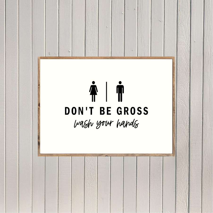 a sign with the text "DON'T BE GOSS" and "WASH YOUR HANDS" written on it, along with two simple pictograms representing a man and a woman.